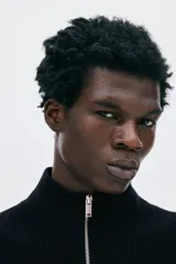 Buzo negro de tejido punto, con cuello alto y cierre metálico parcial frontal. Presenta un corte recto y mangas largas.