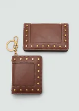 Billetera de tamaño pequeño en color marrón, con diseño de solapa y detalle de tachuelas metálicas doradas en el contorno. Cuenta con compartimento para billetes, múltiples ranuras para tarjetas y bolsillo interior con cierre.