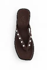 Ojotas de cuero color marrón oscuro con tiras decoradas con tachas metálicas plateadas.