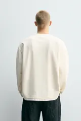 Camiseta de manga larga con corte relajado y cuello redondo. Presenta un diseño de doble capa con acabados en rib a contraste en el cuello y el ruedo.