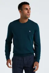 Sweater de tejido liso color verde oscuro (teal) con cuello redondo y manga larga. Presenta un pequeño logo bordado de un pingüino en el pecho.