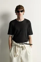 Remera relaxed fit confeccionada en tejido ligero de lyocell, de color negro con cuello redondo, manga corta y acabados en efecto doble combinado a contraste en color blanco.