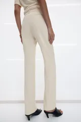 Pantalón de vestir de tiro bajo con corte flare y línea evasé. Confeccionado en mezcla de viscosa, presenta cintura con trabillas, bolsillos delanteros con solapa, bolsillos laterales ocultos y bolsillos de vivo en la parte trasera. Incluye detalle de raya planchada y cierre frontal con cremallera, botón y ganchos metálicos.