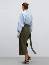 Falda midi verde oliva de lino y algodón, con diseño cruzado y drapeado lateral. Presenta abertura lateral y cierre con lazada.
