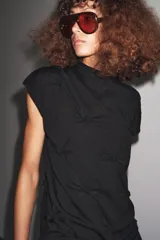 Top negro de manga corta y cuello subido, con detalle de nudos y frunces distribuidos en el frente y laterales, creando textura.