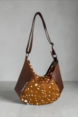 Cartera bandolera de cuero marrón con detalles en cuero con pelo con estampado animal print. Cuenta con diseño geométrico, correa ajustable y cierre superior.