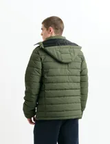 Campera acolchada de color gris, con capucha desmontable, cierre frontal y bolsillos laterales con cremallera. Presenta un diseño de costuras horizontales y detalles en color naranja en los tiradores de los cierres.