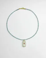 Collar de piedras celestes facetadas en forma de cuentas esféricas, con cierre dorado y un dije colgante rectangular de piedra clara con un detalle circular rojo en el centro.