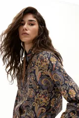 Camisa de algodón con estampado paisley en tonos azules, naranjas y amarillos. Presenta cuello camisero, mangas largas, botones de nácar en el frente y ruedo curvo, más largo en la parte trasera.