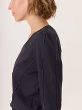 Remera de manga larga color rosado con cuello en V. Presenta detalles de costuras verticales tipo alforzas en el frente y hombros ligeramente fruncidos.