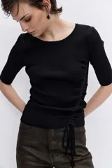 Jersey de tejido acanalado color negro, con cuello redondo, mangas cortas y detalle de jareta lateral ajustable con cordón.