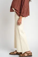 Pantalón de jean color beige, de corte wide leg con botamanga desflecada y tiro medio, diseñado especialmente para maternidad.