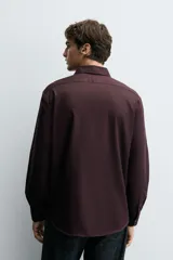 Camisa blanca de manga larga con cuello italiano y cierre frontal de botonadura. Corte regular fit.