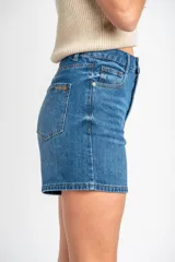 Short de denim azul de tiro medio y calce ajustado, con cinco bolsillos y cierre frontal con botón y cremallera.