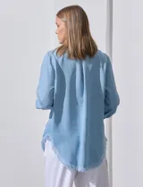 Camisa celeste de tencel, marca Hester & Orchand. Tiene cuello con solapa, escote en V, abertura central con botones, bolsillo aplicado en el frente y ruedo desflecado.