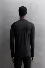 Camiseta negra de running de primera capa, confeccionada en tejido elástico y ajustado al cuerpo. Tiene cuello alto con logo estampado, mangas largas con puños ajustables y costuras planas.