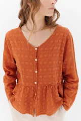 Camisa color crema con bordados florales, escote en V, mangas largas y cierre frontal con botones.