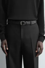 Cinturón de piel color negro con hebilla metálica plateada de forma rectangular y pasador a juego.