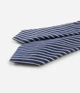 Corbata de diseño clásico con estampado de rayas diagonales en azul marino y blanco. Presenta un acabado satinado y una estructura ligera, ideal para complementar atuendos formales o casuales.