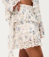 Pollera corta evasé de encaje floral Liberty, con volados asimétricos en capas y forro interno.