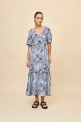 Vestido largo celeste con estampado botánico en tonos marrones, escote en V, mangas cortas abullonadas y falda con volado en el bajo.
