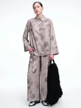 Camisa oversize de lyocell con estampado orgánico efecto lavado. Presenta cuello clásico, cierre frontal con botones, mangas amplias con puños anchos y un diseño de corte relajado con ruedo asimétrico, siendo más largo en la parte posterior.