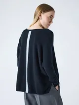 Sweater tejido de calce holgado con escote en V, mangas largas y tajos laterales en el ruedo. Presenta un diseño minimalista con detalle a contratono en la espalda.