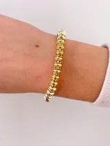 Pulsera elástica de cuentas metálicas doradas intercaladas con aros de strass, con dije colgante del árbol de la vida y una pequeña esfera lisa.
