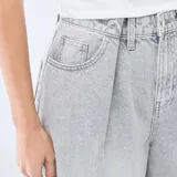Jean de corte wide leg y tiro alto, confeccionado en denim de color gris lavado. Presenta pinzas en la cintura, cierre frontal con botón y bolsillos laterales.
