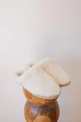 Pantuflas de corderito color blanco, ideales para usar en casa.