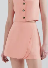 Falda corta tipo short pollera color salmón con diseño cruzado tipo envolvente en el frente.