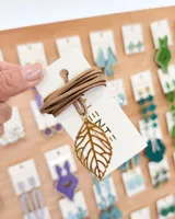 Choker con tiento de gamuza color tostado y dije de hoja calada color dorado.