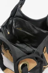 Bolso oversize negro de canvas con diseño de sol en eco-cuero marrón aplicado en el frente, bordeado con tachas metálicas. Cuenta con asas de hombro y detalles de herrajes en tono bronce.