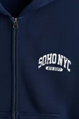 Campera con capucha y cierre frontal de color azul marino, corte oversized, bolsillos tipo canguro y estampado universitario "SOHO NYC ATH DEPT" en el pecho.