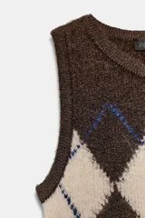 Chaleco de punto color marrón oscuro con diseño de rombos en beige y líneas azules. Tiene cuello redondo y manga sisa.