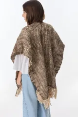 Ruana artesanal tejida en telar con lana hilada a rueca por tejedoras rurales de Uruguay. Diseño con patrón a cuadros en tonos marrón y crudo, con flecos en los extremos.