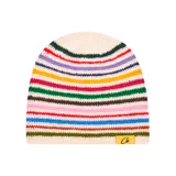 Gorro tipo beanie tejido a crochet con diseño de rayas horizontales multicolor sobre base color crema. Incluye una etiqueta rectangular amarilla con el logo de la marca en la parte inferior.