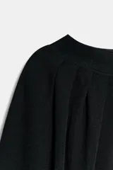 Top corto negro de punto fino, con cuello redondo y mangas largas abullonadas con pliegues.