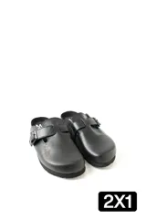 Zuecos de cuero negro con diseño cerrado en la punta, ajuste mediante tira con hebilla lateral y suela plana de goma.