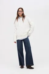 Buzo de punto color blanco, con diseño de ochos, cuello redondo y calce holgado. Presenta detalles en color contrastante en las sisas y el ruedo.