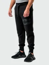 Pantalón de jogging negro de algodón con cintura elástica ajustable con cordón, bolsillos laterales y banda horizontal con logo de la marca en el muslo izquierdo.