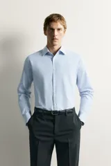 Camisa negra de corte regular fit, cuello italiano, manga larga con puño abotonado y cierre frontal con botones.