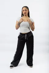 Pantalón negro de corte recto y holgado, con cintura elástica ajustable con cordón blanco y dos franjas blancas laterales.