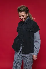Chaleco de jean oversized color negro, con cuello camisero y cierre frontal con botones metálicos. Presenta un diseño estructurado con costuras reforzadas.