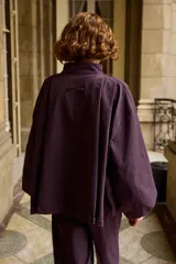 Campera de corte holgado y diseño minimalista en color marrón, con cuello alto, cierre frontal oculto y mangas largas con puños ajustados.