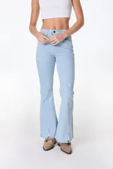 Jean azul claro de corte flare con aberturas en los tobillos y detalles rotos en las rodillas y muslos.