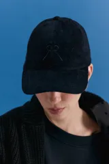 Gorra tipo cap confeccionada en corderoy negro, con isologo bordado a tono en el frente y tira de ajuste con hebilla metálica en la parte posterior.