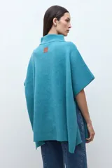 Sweater oversized color verde petróleo, con cuello alto y cierre frontal corto.