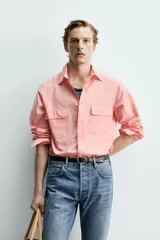 Camisa de corte relajado color celeste, confeccionada en mezcla de algodón y seda. Presenta cuello solapa, cierre frontal de botones, manga larga con puños abotonados y dos bolsillos de plastrón con solapa en el pecho.