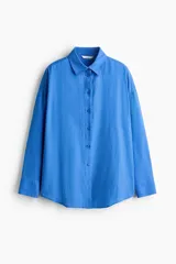 Camisa de lino y viscosa color azul, de corte oversized y diseño liviano, con cuello clásico, cierre frontal de botones, hombros caídos y mangas largas con puños abotonados.